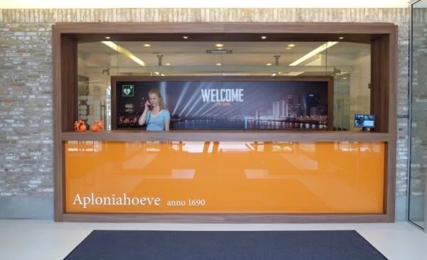 Receptiebalie van Aploniahoeve aan de Charloisse Lagedijk met een welkomstbord en skyline van Rotterdam op de achtergrond.